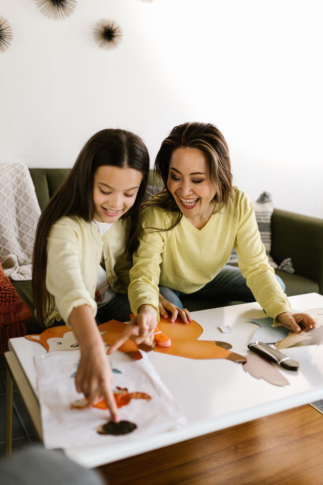 A mother and daughter laughing over a craft project