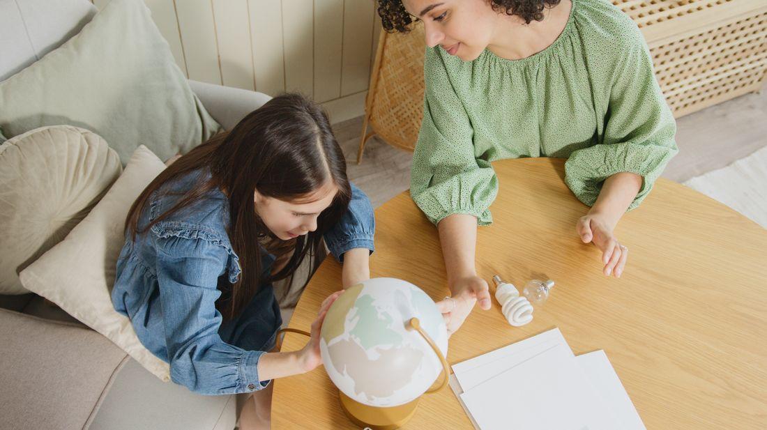 A mother and daughter exploring a globe during a lesson
